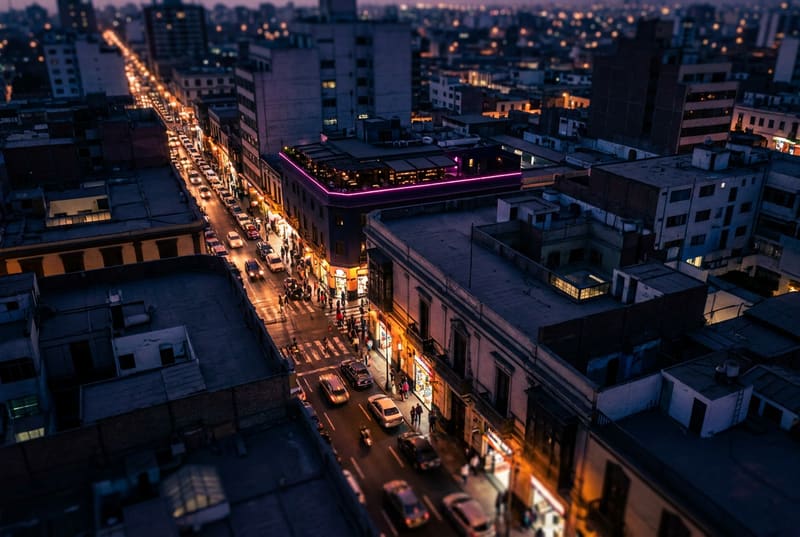 Vista nocturna de una avenida de la ciudad con las luces de los negocios encendidas